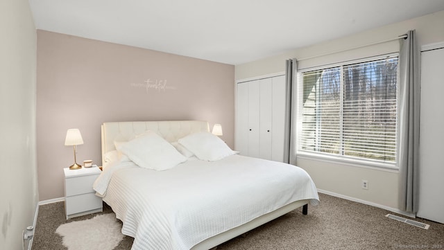 carpeted bedroom with baseboards, multiple windows, a closet, and visible vents