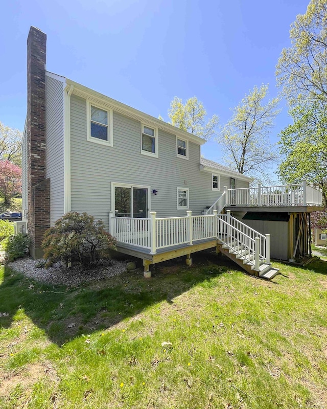rear view of house with stairs, a wooden deck, a yard, and a chimney
