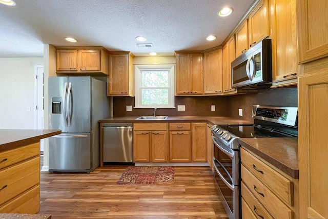 kitchen with dark countertops, appliances with stainless steel finishes, a sink, tasteful backsplash, and visible vents