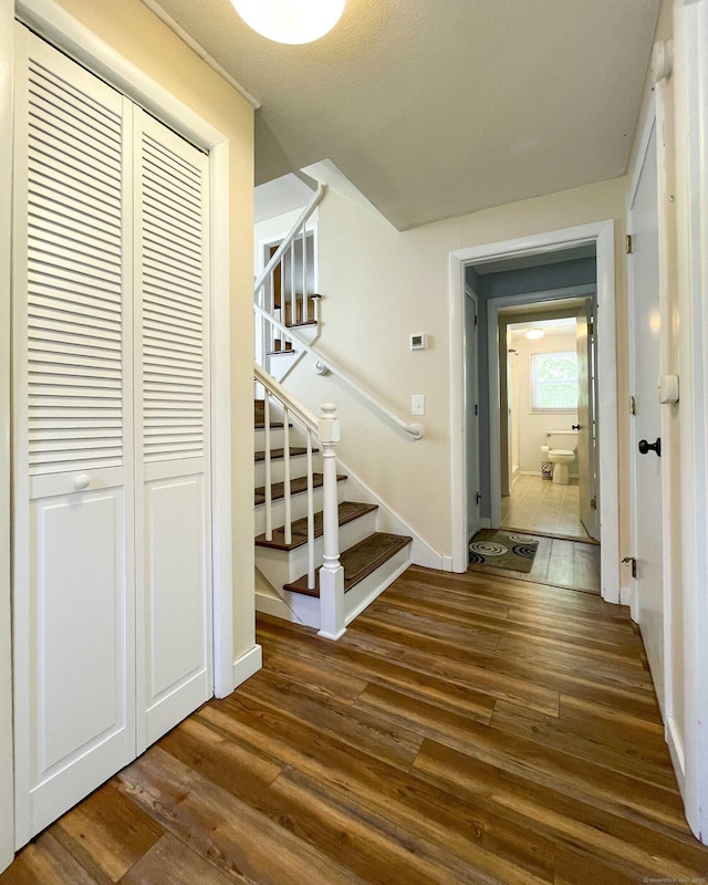 hallway with baseboards, dark wood finished floors, and stairway