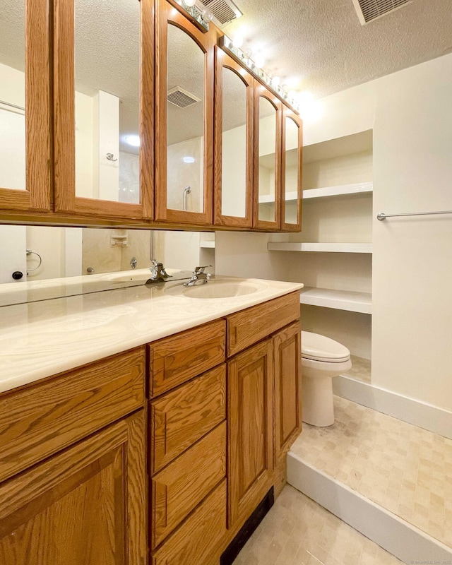 bathroom with toilet, a textured ceiling, and visible vents