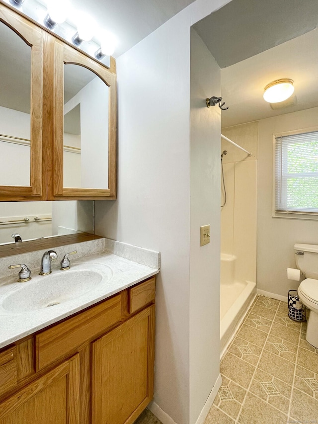 bathroom with vanity, baseboards, walk in shower, and toilet