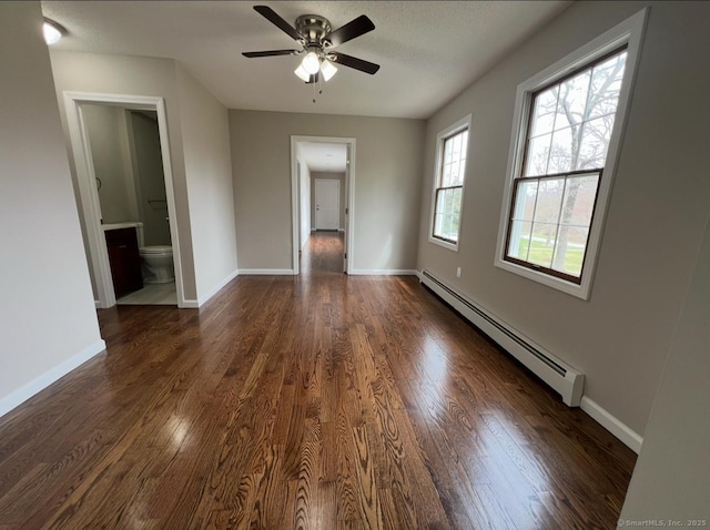 unfurnished room featuring baseboards, ceiling fan, a baseboard heating unit, and dark wood-style flooring