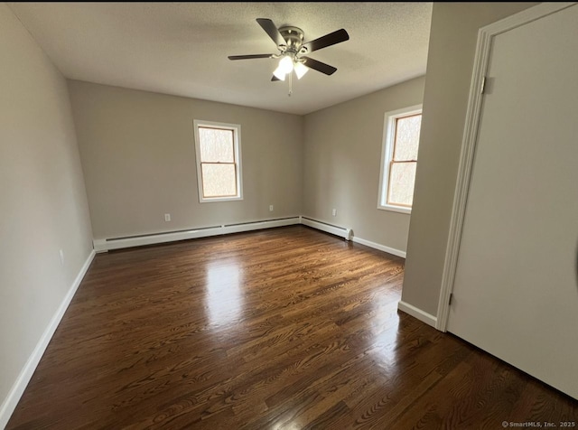 spare room featuring baseboards, a ceiling fan, dark wood-style flooring, and baseboard heating