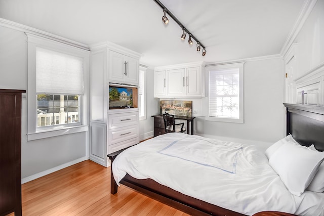 bedroom featuring light wood finished floors, track lighting, and baseboards