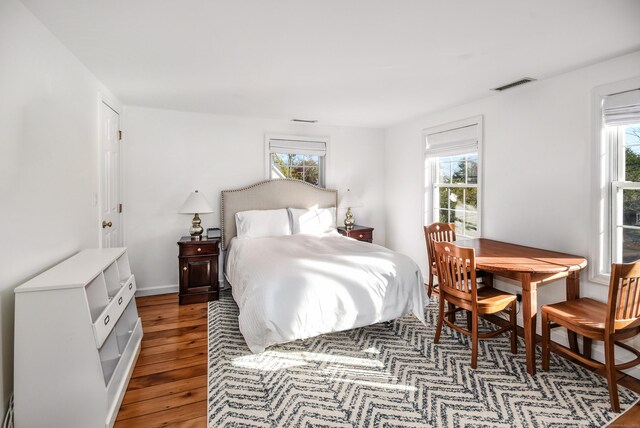 bedroom with multiple windows and light wood-style floors