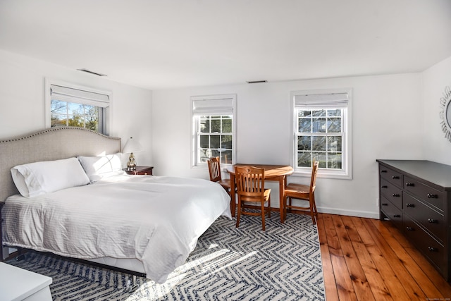 bedroom featuring multiple windows, hardwood / wood-style flooring, and baseboards