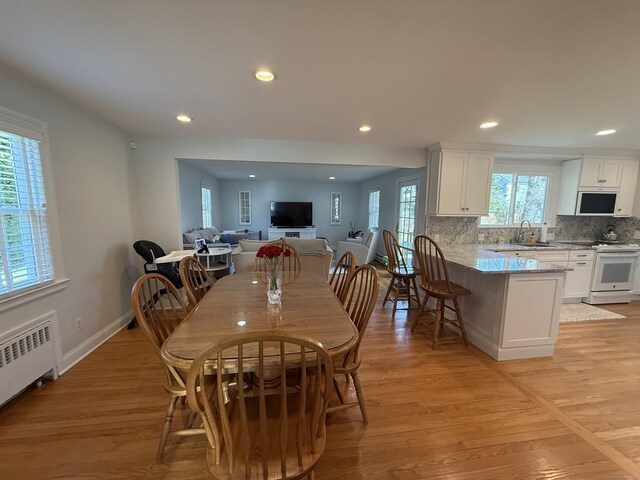dining space featuring recessed lighting, light wood-style flooring, radiator, and baseboards