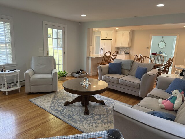 living area featuring recessed lighting, a baseboard radiator, light wood finished floors, and a healthy amount of sunlight