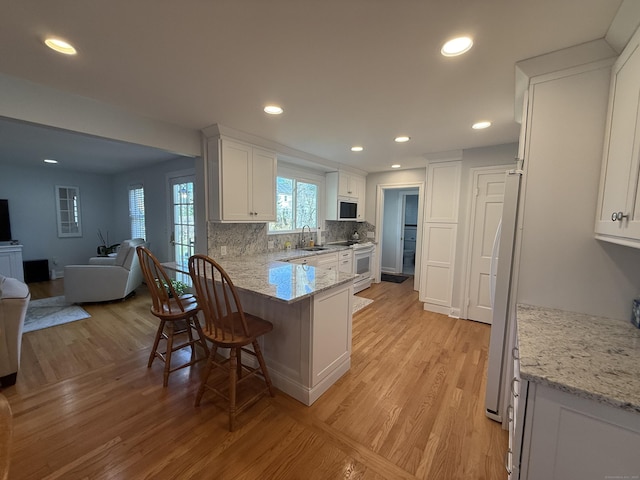 kitchen with white appliances, open floor plan, a sink, and light wood-style flooring