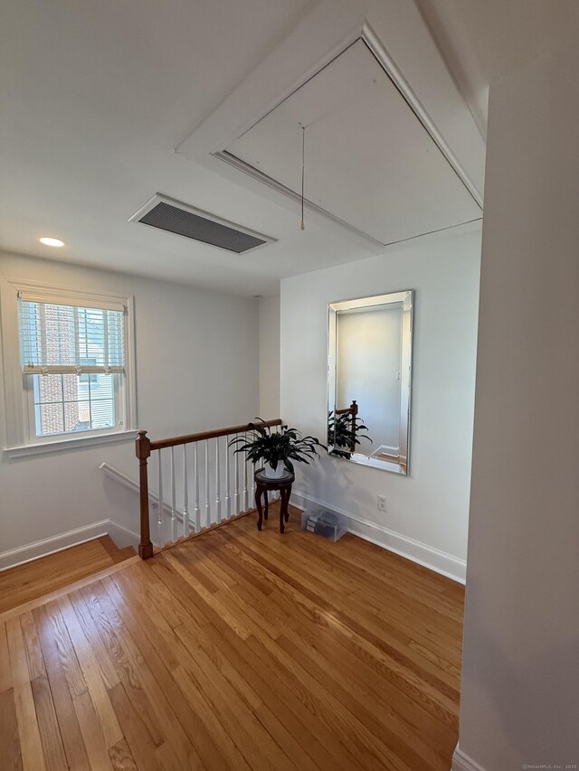 spare room featuring baseboards, attic access, and wood finished floors