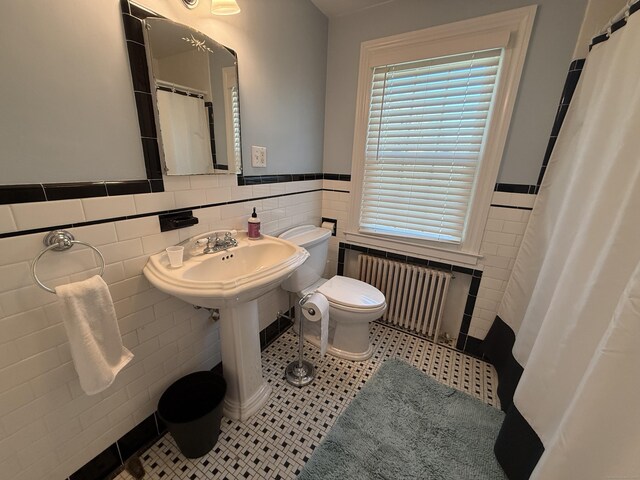 bathroom featuring radiator heating unit, tile walls, a wainscoted wall, and toilet