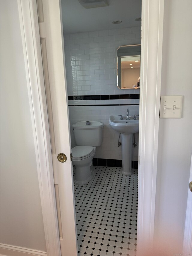 bathroom featuring tile patterned flooring, a sink, toilet, and tile walls