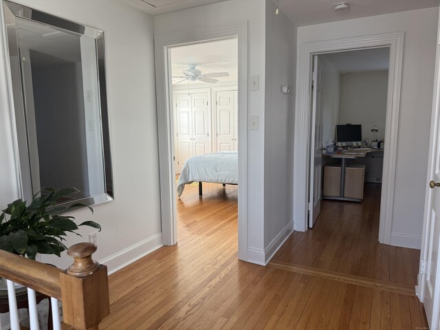 hall featuring attic access, baseboards, and light wood finished floors