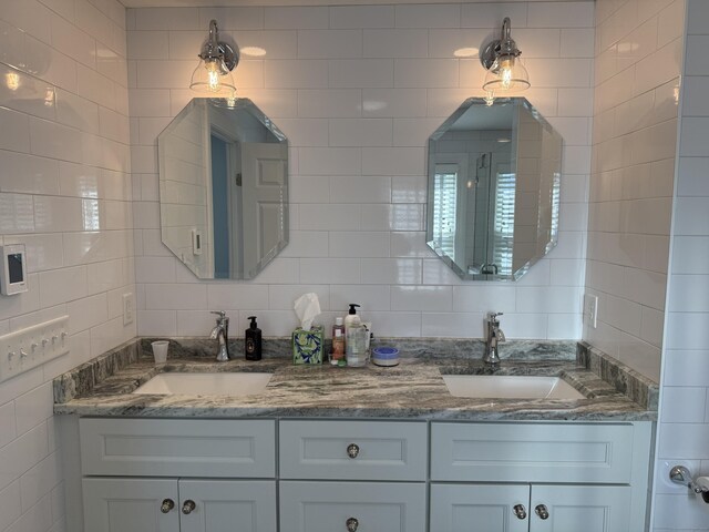 bathroom featuring double vanity, a sink, and tile walls
