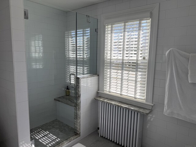 bathroom with radiator, tile walls, and a shower stall