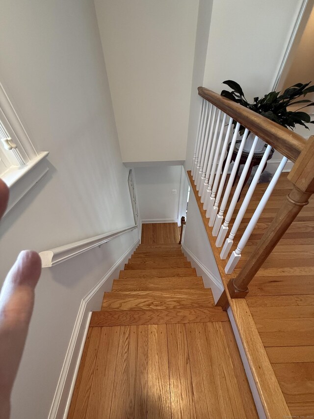 staircase featuring baseboards and wood finished floors