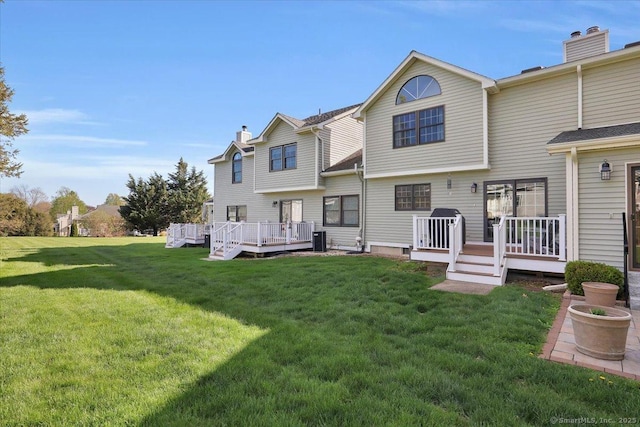 back of property featuring a lawn, a wooden deck, and a chimney