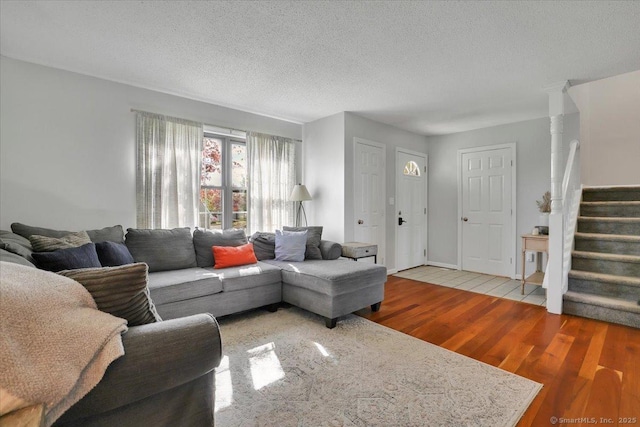 living room featuring stairs, a textured ceiling, and wood finished floors