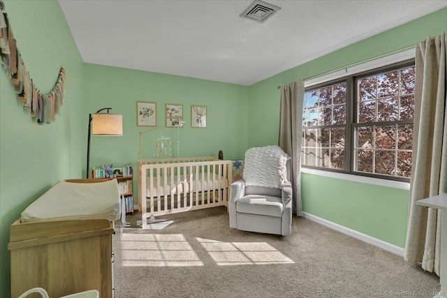 carpeted bedroom featuring visible vents, baseboards, and a nursery area