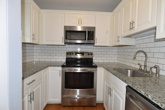 kitchen featuring appliances with stainless steel finishes, a sink, and white cabinetry