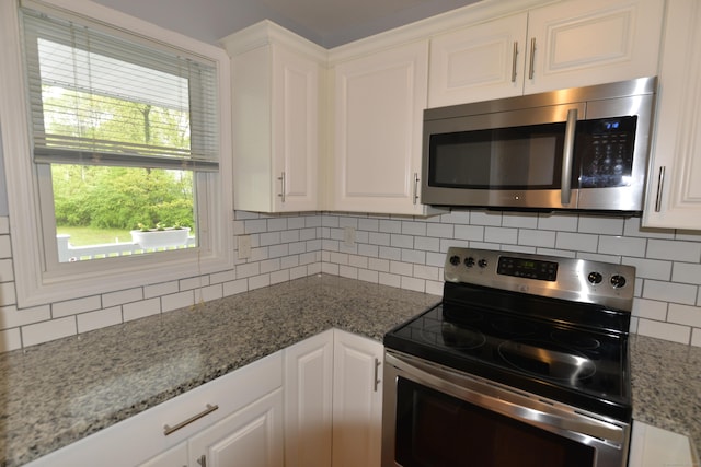 kitchen featuring appliances with stainless steel finishes, decorative backsplash, white cabinets, and light stone countertops
