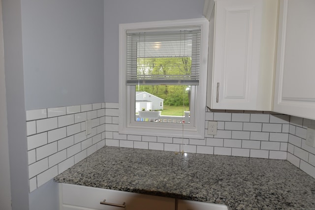 kitchen view of stone countertops, white cabinets, and backsplash
