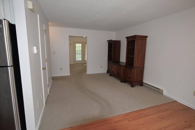 unfurnished living room featuring a baseboard heating unit, baseboards, and light wood finished floors