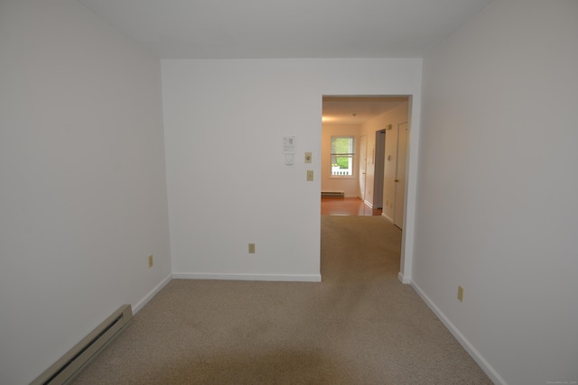 unfurnished room featuring baseboard heating, light carpet, and baseboards