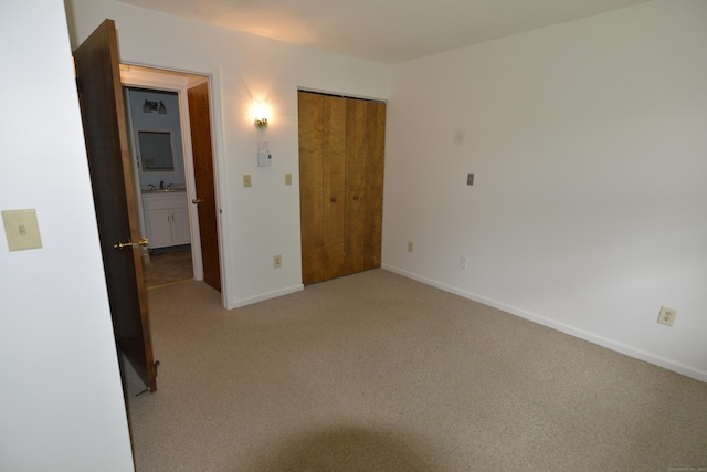 unfurnished bedroom with light colored carpet, baseboards, and a closet