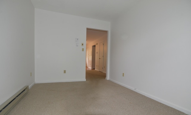 empty room with a baseboard radiator, light colored carpet, and baseboards