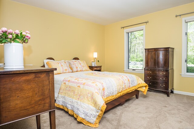 bedroom with baseboards and light carpet