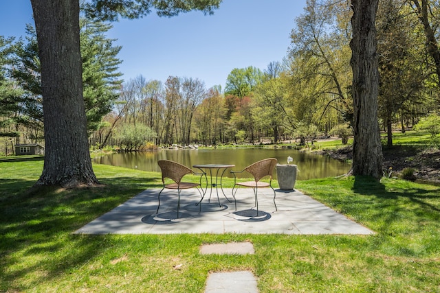 view of community featuring a patio, a water view, and a yard
