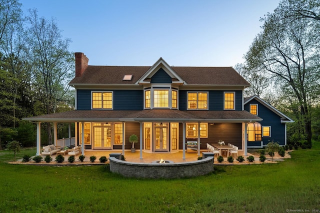 82 Indian Hill Rd, Wilton, CT 06897 - back of property at dusk with french doors, a yard, a chimney, and a patio