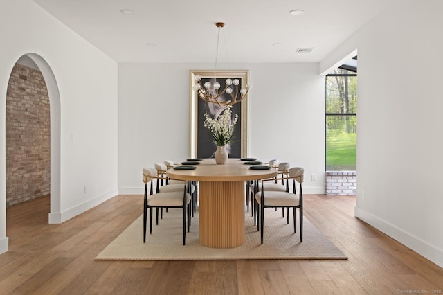 82 Indian Hill Rd, Wilton, CT 06897 - dining space with light wood-style floors, baseboards, arched walkways, and brick wall