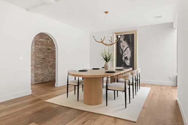 82 Indian Hill Rd, Wilton, CT 06897 - dining area with light wood finished floors, arched walkways, baseboards, and a chandelier