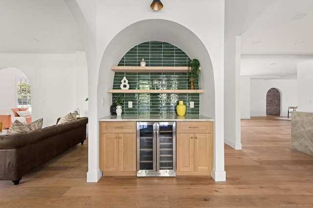 82 Indian Hill Rd, Wilton, CT 06897 - indoor bar with beverage cooler, arched walkways, light wood-type flooring, tasteful backsplash, and baseboards
