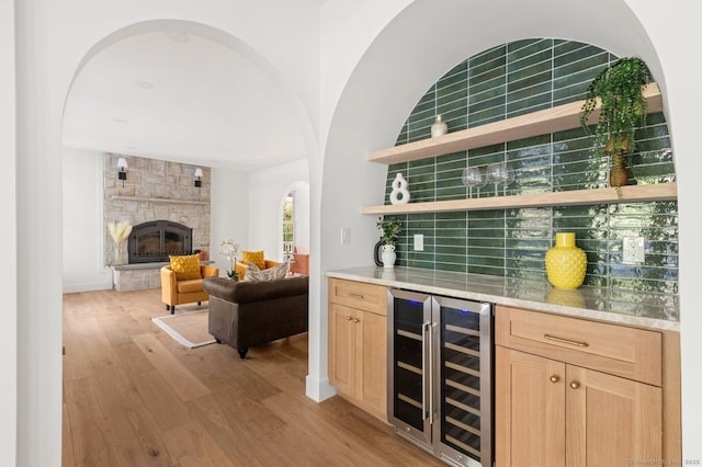 82 Indian Hill Rd, Wilton, CT 06897 - indoor dry bar featuring beverage cooler, light wood finished floors, a fireplace, backsplash, and arched walkways
