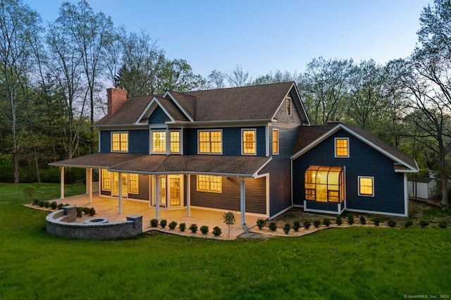 82 Indian Hill Rd, Wilton, CT 06897 - back of property at dusk featuring a chimney, a lawn, and a porch