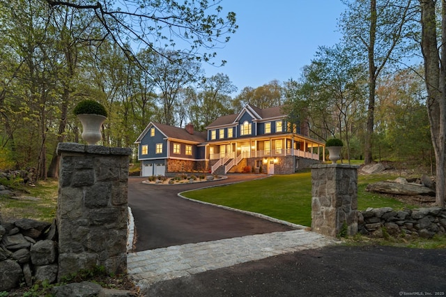 view of front of home featuring driveway, an attached garage, a chimney, and a front yard
