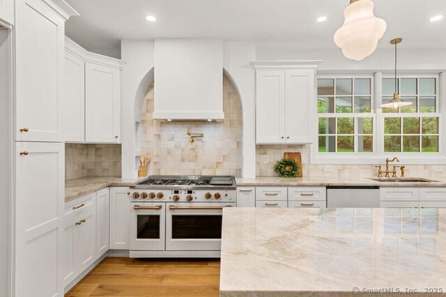 82 Indian Hill Rd, Wilton, CT 06897 - kitchen with double oven range, a sink, dishwashing machine, arched walkways, and white cabinetry