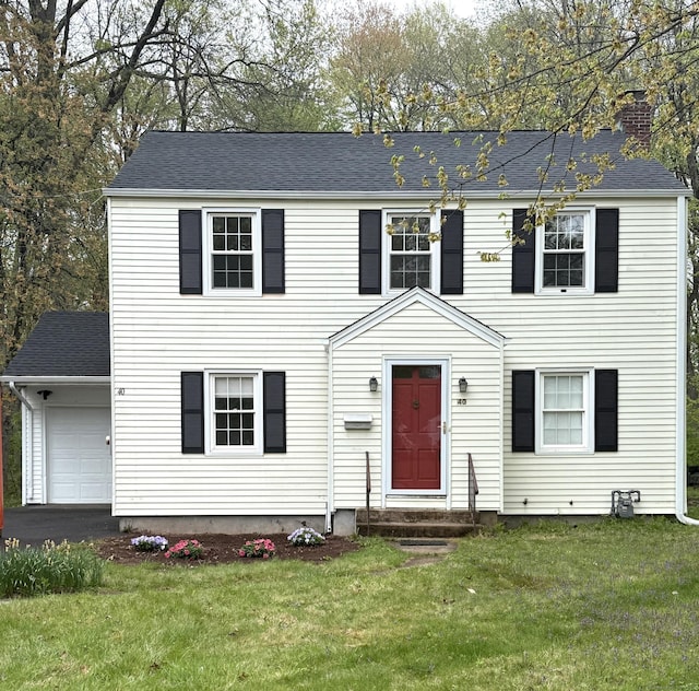colonial home featuring a garage, a front lawn, a chimney, entry steps, and driveway