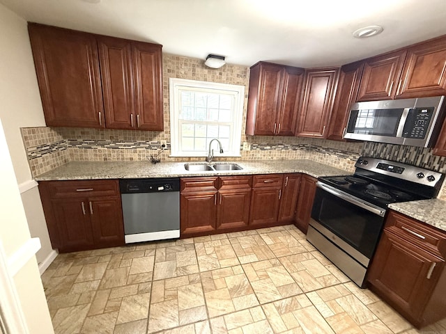 kitchen with a sink, backsplash, light stone countertops, and stainless steel appliances