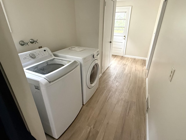 washroom with laundry area, washer and clothes dryer, light wood-style flooring, and baseboards