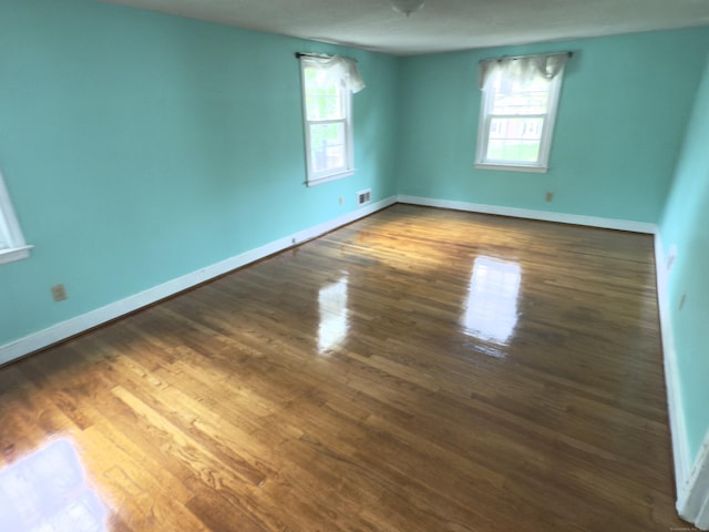 spare room featuring baseboards, wood finished floors, and visible vents