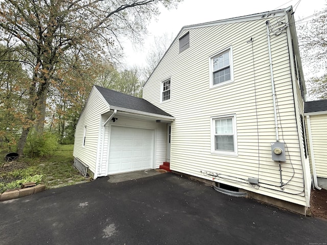 view of side of home featuring an outbuilding, an attached garage, and driveway