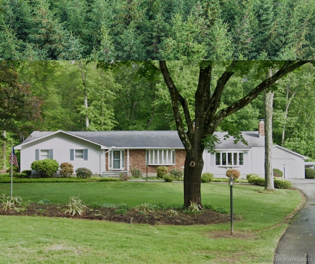 ranch-style house featuring a shingled roof, a chimney, a front lawn, and brick siding