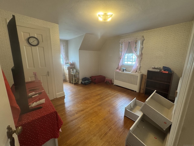 34 Knollwood Rd, East Hartford, CT 06118 - bedroom featuring radiator heating unit, wood finished floors, lofted ceiling, and wallpapered walls