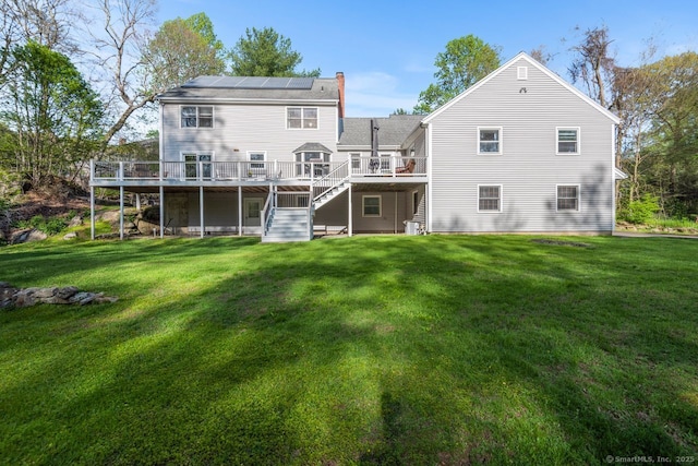 95 Pepperidge Cir, Stratford, CT 06614 - back of property with a wooden deck, stairs, a lawn, and roof mounted solar panels