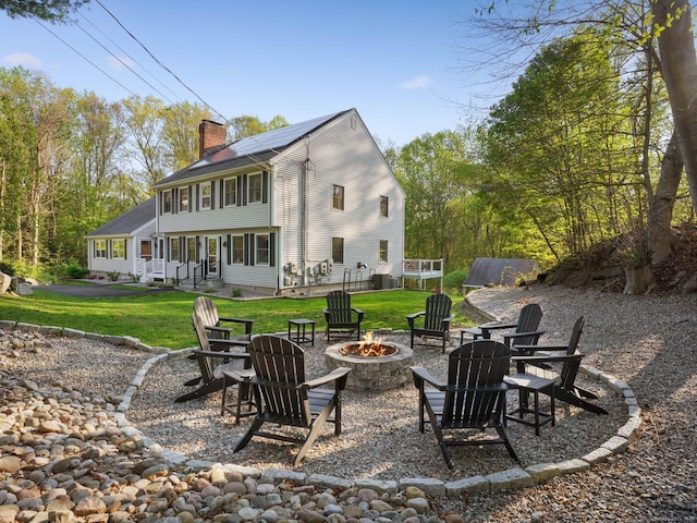 95 Pepperidge Cir, Stratford, CT 06614 - rear view of house featuring roof mounted solar panels, a chimney, a yard, and a fire pit